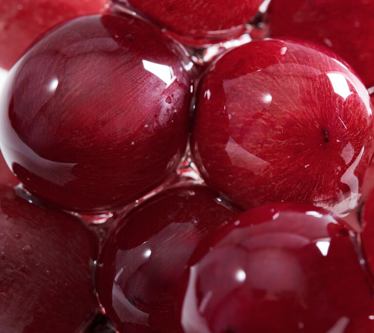 Close-up of glossy red grapes clustered together with visible reflections and water droplets